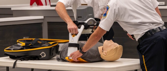 The two firefighters place the CPR dummy in the LUCAS device