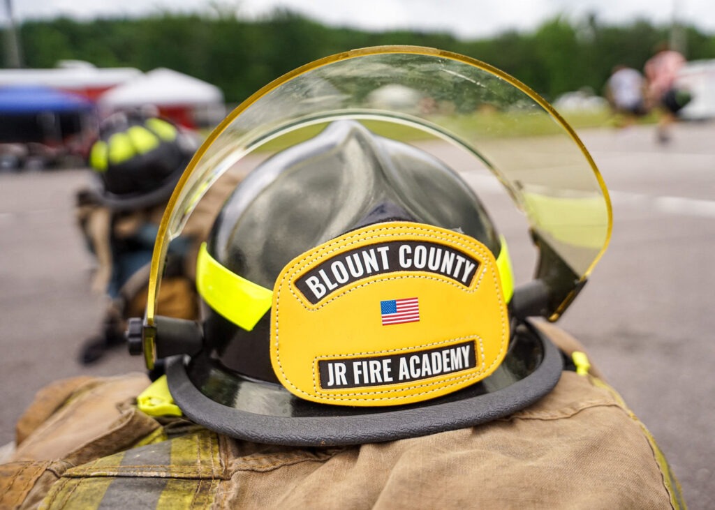 A folded fire suit with a fire hat on top that reads "Blount County Jr Fire Academy"