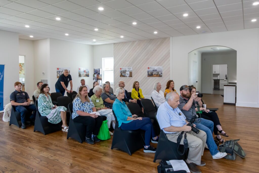 Crowd of grantees and media sit in chairs facing forward in the Jasper Main Street office