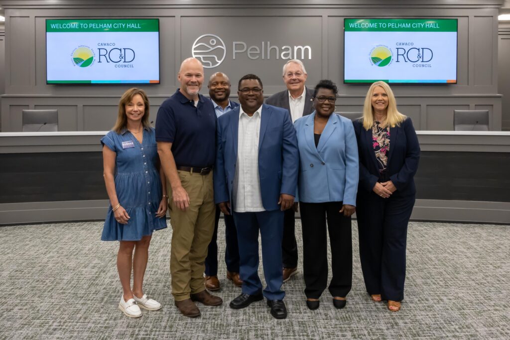 Representatives from Calera Main Street stand with Shelby County legislators at the grant presentation ceremony, posing at the front of Pelham City Council Chambers
