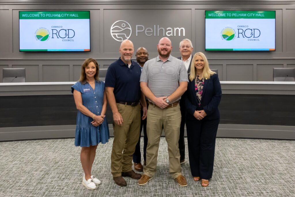 A representative from Shelby County High School stands with Shelby County legislators at the grant presentation ceremony, posing at the front of Pelham City Council Chambers
