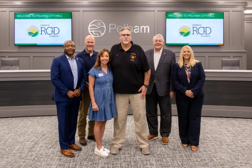 A representative from Dunnavant FIre District stands with Shelby County legislators at the grant presentation ceremony, posing at the front of Pelham City Council Chambers