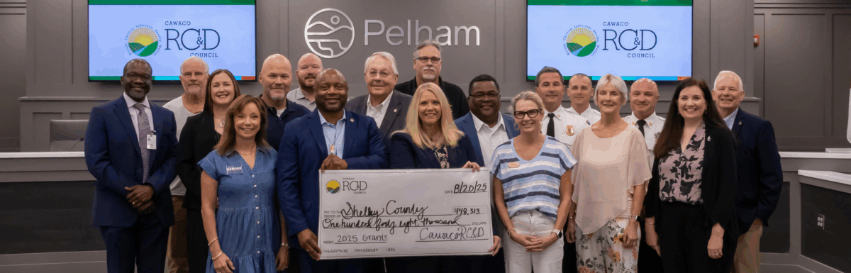 Shelby County attendees gathered at the front of Pelham City Hall's Chambers for the presentation of a large symbolic check