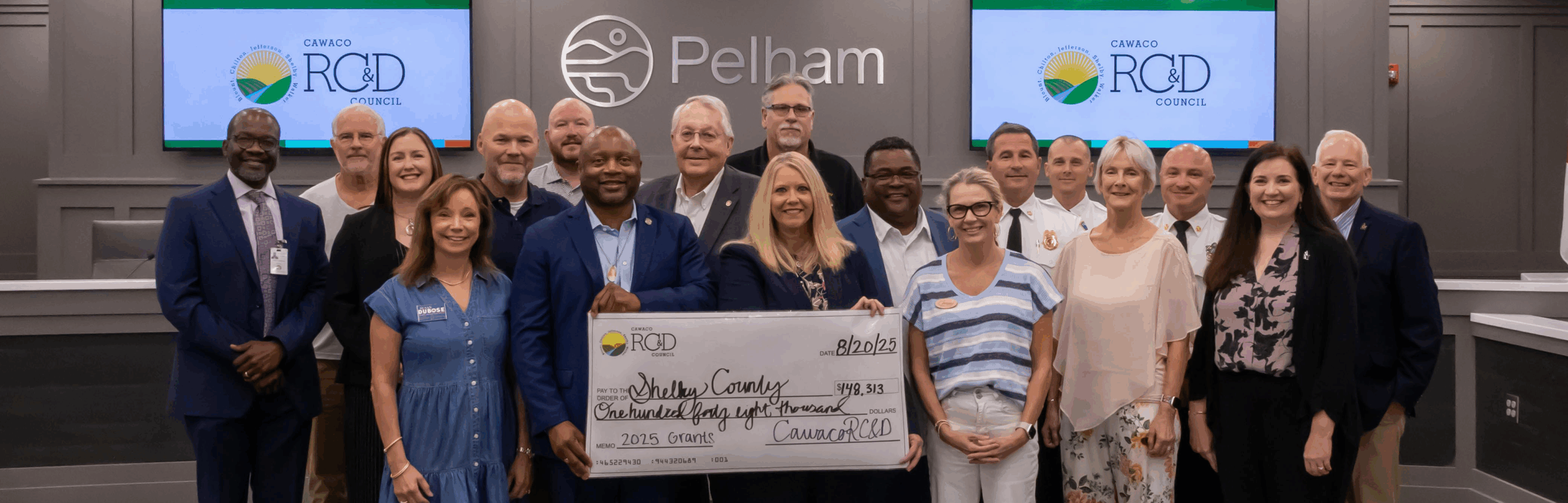 Shelby County attendees gathered at the front of Pelham City Hall's Chambers for the presentation of a large symbolic check
