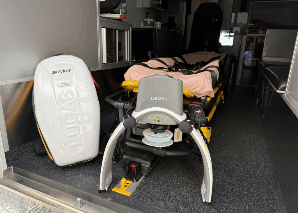 A LUCAS device sitting next to a stretcher in an emergency vehicle