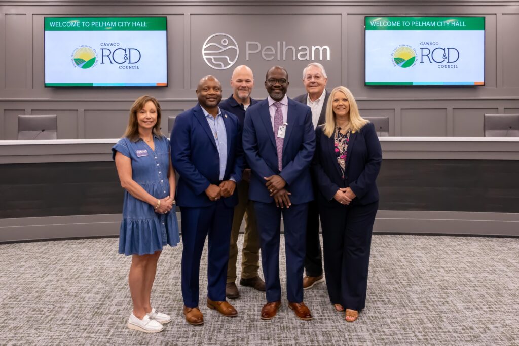 A representative from the Linda Nolen Learning Center stands with Shelby County legislators at the grant presentation ceremony, posing at the front of Pelham City Council Chambers
