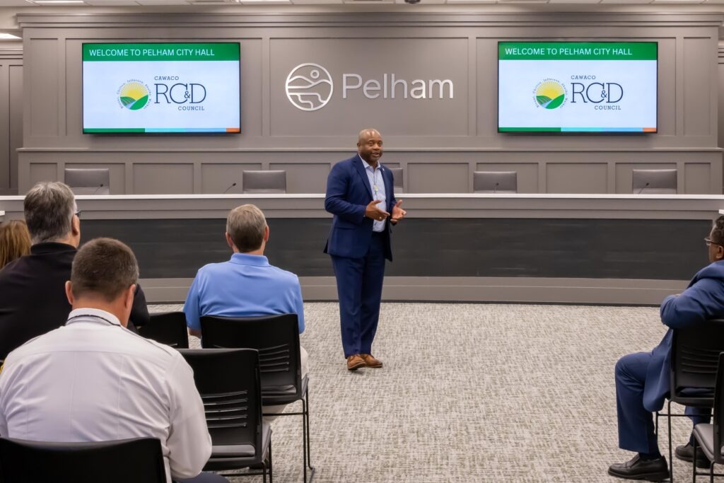Rep. Kenneth Paschal stands at the front of the Pelham City Council Chambers and speaks to the crowd