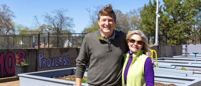 Michelle Barnes and Frank Long stand together smiling among the new raised garden beds on the Lovelady Center rooftop on a sunny day.