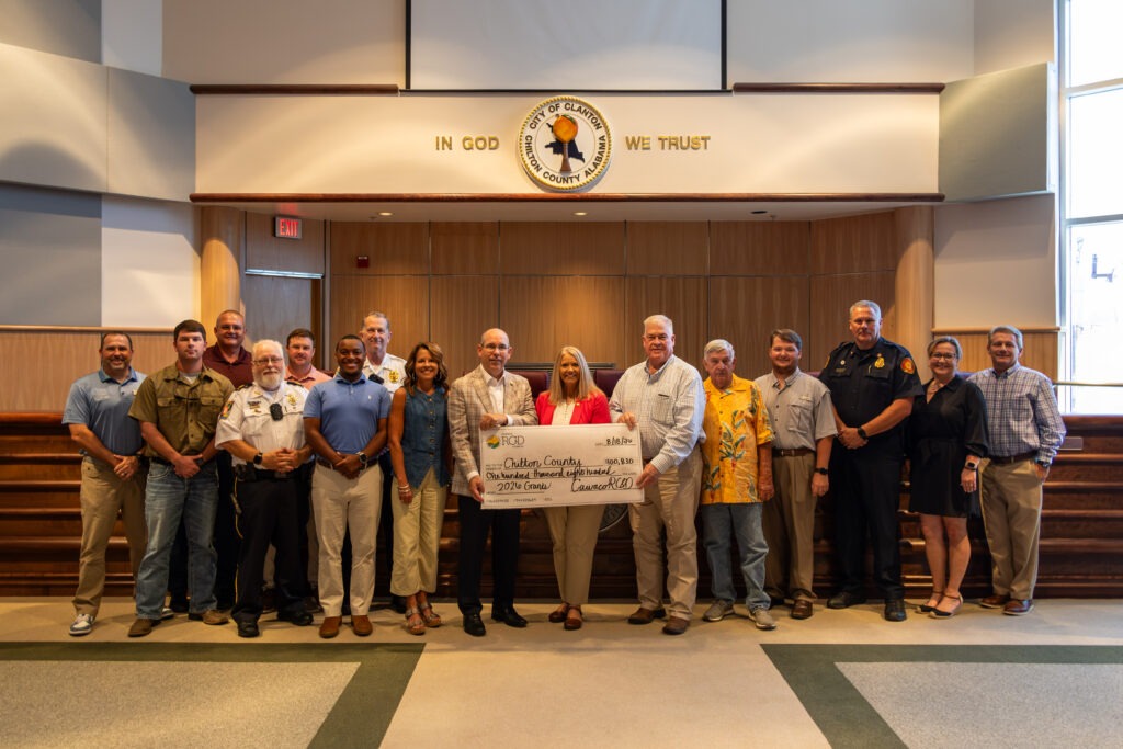 Legislators, public safety officials, and community members hold a ceremonial check for $100,830 from Cawaco RC&D to Chilton County for 2026 grants, in the Clanton City Council chambers.