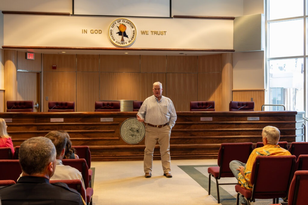 Rep. Van Smith stands at the front of the CIty of Clanton Council Chambers, addressing Chilton County grantees