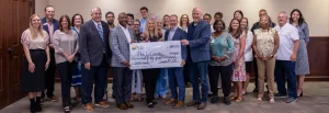 Legislators and grant recipients pose in a Calera City Hall meeting room. Four legislators in the center hold an oversized check from Cawaco RC&D to Shelby County for $144,950 with the memo "2026 Grants."