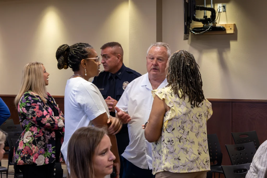 Mayor of Calera, Cawaco Board Chair Sheila Baker, and grantee discuss in a small circle before the meeting