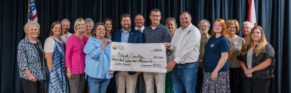 Representatives of Cawaco RC&D, the Blount County Legislative Delegation, and grant recipients stand on stage holding a large ceremonial check for $152,456 made out to Blount County for 2026 grants.
