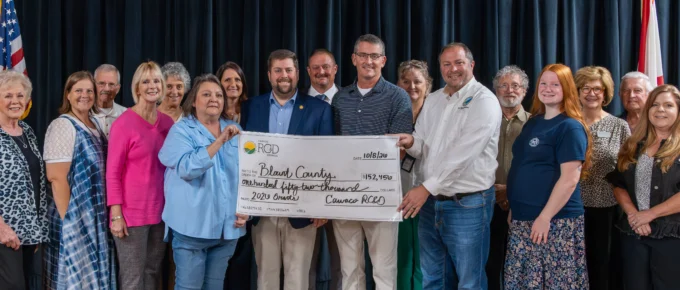 Representatives of Cawaco RC&D, the Blount County Legislative Delegation, and grant recipients stand on stage holding a large ceremonial check for $152,456 made out to Blount County for 2026 grants.